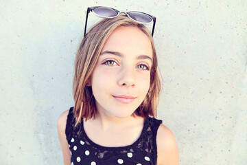 Portrait of a teenage argentinian girl wearing sunglasses and a polka dot dress, isolated over cement background. Copy space. - Powered by Adobe