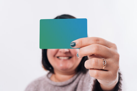 Funny image of a woman covering her eyes with a green credit card and showing a smile. Online shopping concept
