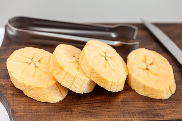 Closeup ripe plantain pieces over a wooden cutting board
