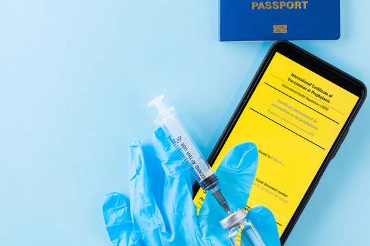 Vaccination concept. Yellow international certificate of vaccination, vaccine vial and syringe. Vaccine bottle, syringe and passport on a blue background. Immunity passport