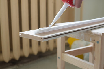 Process of installing ceiling skirting board. Place glue on it.
