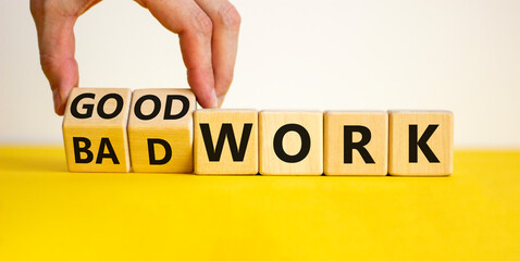 Good or bad work symbol. Businessman turns wooden cubes and changes words 'bad work' to 'good work'. Beautiful yellow table, white background, copy space. Business and good or bad work concept.