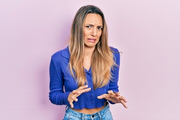 Beautiful hispanic woman wearing casual blue shirt disgusted expression, displeased and fearful...