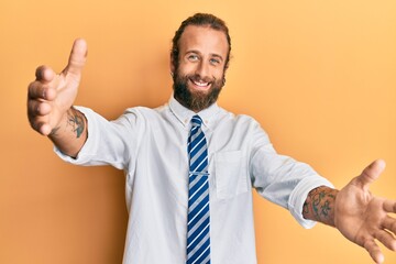 Handsome man with beard and long hair wearing business clothes looking at the camera smiling with open arms for hug. cheerful expression embracing happiness.