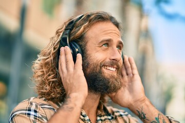 Young caucasian man smiling happy using headphones at the city.