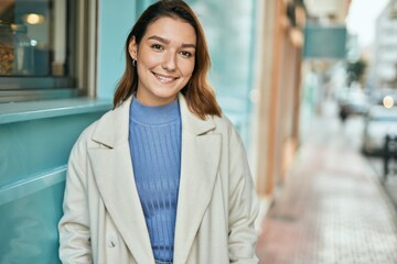 Young hispanic woman smiling happy standing at the city