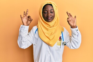 Beautiful african young woman wearing doctor uniform and hijab relaxed and smiling with eyes closed doing meditation gesture with fingers. yoga concept.
