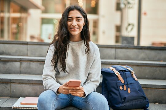 Young middle east student girl smiling happy using smartphone at the city.