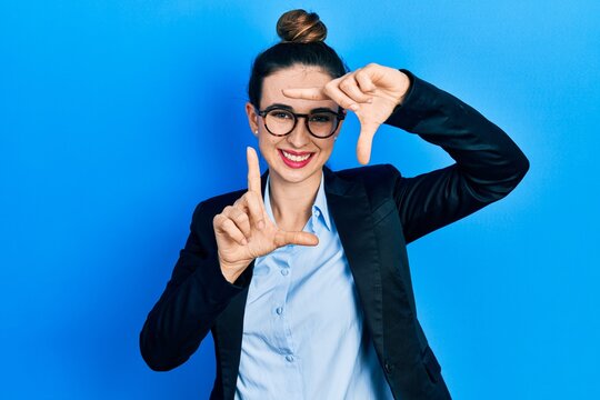 Young hispanic girl wearing business clothes and glasses smiling making frame with hands and fingers with happy face. creativity and photography concept.