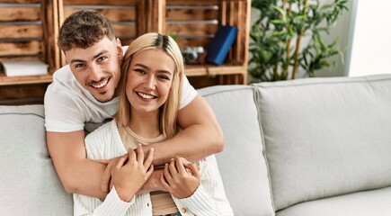 Fototapeta na wymiar Young caucasian couple smiling happy and hugging sitting on the sofa at home.
