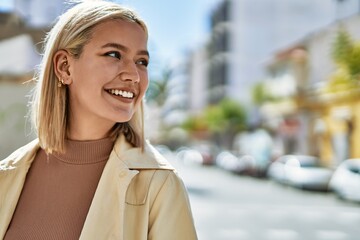 Young blonde girl smiling happy standing at the city.