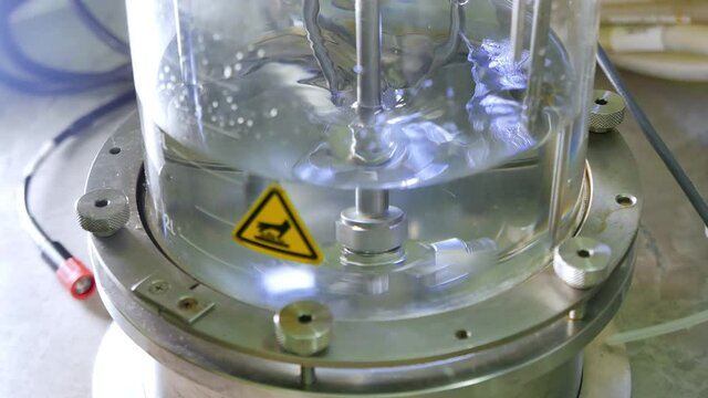 Liquid bioreactor, glass cylinder with mixing liquid inside. Science experiment in laboratory. Synthesis of new substances