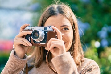 Young hispanic tourist woman smiling happy using vintage camera at the city.