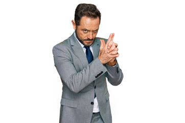 Middle age man wearing business clothes holding symbolic gun with hand gesture, playing killing shooting weapons, angry face