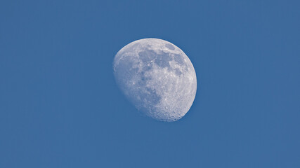 Closeup of waxing gibbous moon during daytime against clear blus sky - Stuttgart, Germany May 22,...
