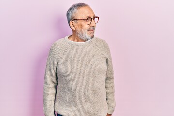 Fototapeta premium Handsome senior man with beard wearing casual sweater and glasses smiling looking to the side and staring away thinking.