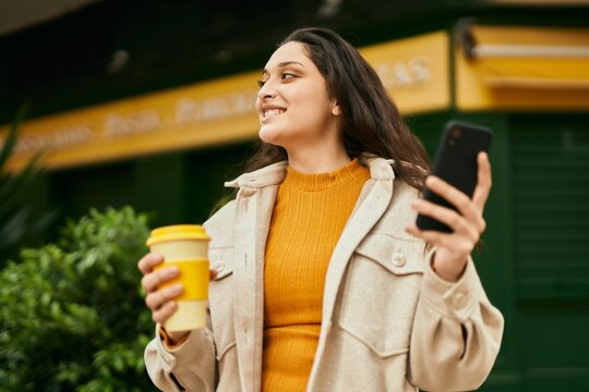 Young middle east woman using smartphone drinking coffee at the city.