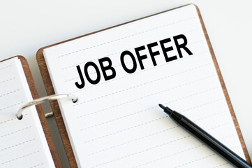 Motivational words: JOB OFFER on the notebook next to a black marker. Business and finance concept
