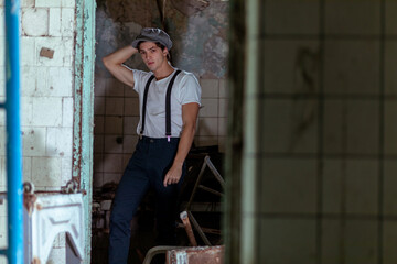 Joven en construcción abandonada vestido con gorro tiradores y camiseta
