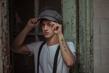Joven se acomoda el gorro y esta vestido con tiradores y camiseta