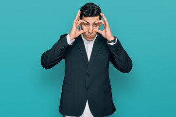 Handsome hispanic man wearing business clothes trying to open eyes with fingers, sleepy and tired for morning fatigue