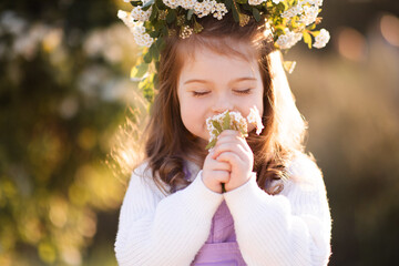 Cute kid girl 2-3 year old smell flowers over green nature background close up. Spring season....