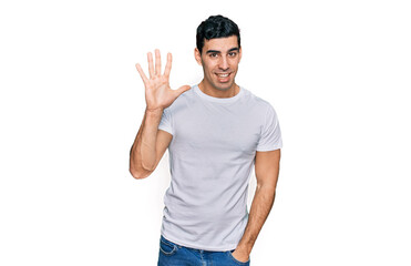 Handsome hispanic man wearing casual white t shirt showing and pointing up with fingers number five...