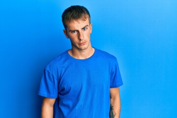 Young caucasian man wearing casual blue t shirt skeptic and nervous, frowning upset because of problem. negative person.