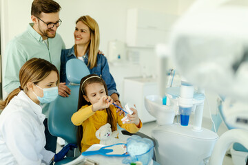 Oral hygienist with jaw model teaching patients to brush teeth properly to prevent caries.