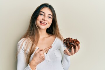 Young caucasian woman holding bowl of star anise smiling happy pointing with hand and finger