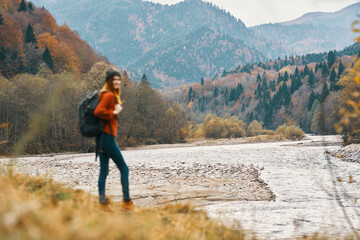 Obraz premium woman travels in autumn in the mountains near the river landscape model in full growth