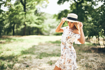 beautiful tender young woman in summer dress and straw hat posing outdoor. Awesome warm summer day