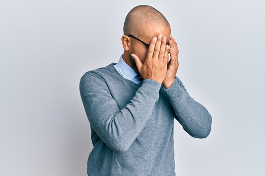 Hispanic adult man wearing glasses and business style with sad expression covering face with hands while crying. depression concept.