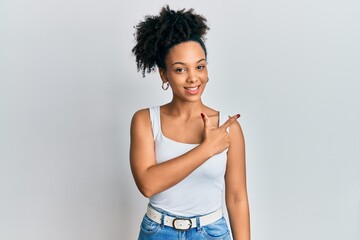 Young african american girl wearing casual style with sleeveless shirt smiling cheerful pointing with hand and finger up to the side