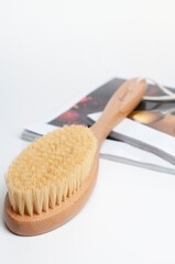 wooden brush for body on the white towel in the white background with magazines