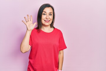 Middle age hispanic woman wearing casual clothes showing and pointing up with fingers number five while smiling confident and happy.