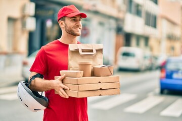 Young caucasian deliveryman smiling happy holding delivery food at the city.