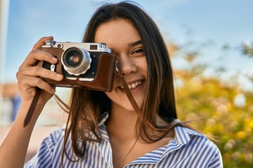 Young hispanic tourist girl smiling happy using camera at the park