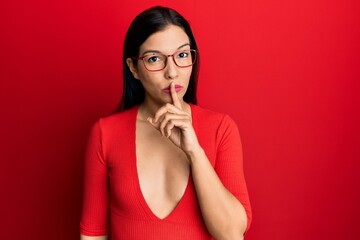 Young latin woman wearing casual clothes and glasses asking to be quiet with finger on lips. silence and secret concept.