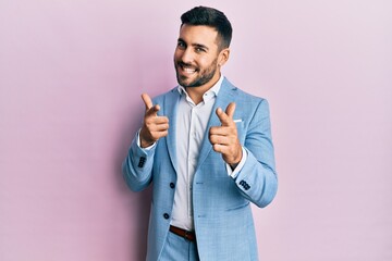 Young hispanic businessman wearing business jacket pointing fingers to camera with happy and funny face. good energy and vibes.