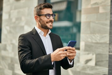 Young hispanic businessman smiling happy using smartphone at the city.