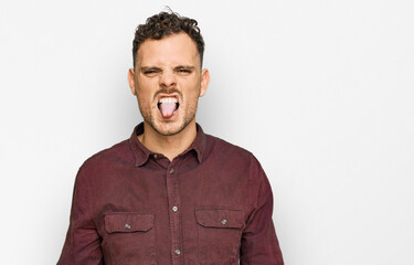 Obraz premium Young hispanic man wearing casual clothes sticking tongue out happy with funny expression. emotion concept.