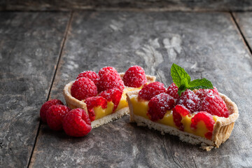 Fresh homemade fruit tart with raspberry and lemon curd on wooden table
