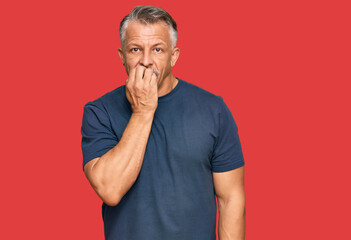 Middle age grey-haired man wearing casual clothes looking stressed and nervous with hands on mouth...