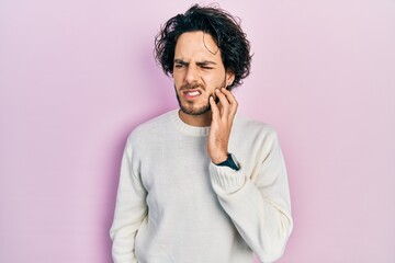 Fototapeta na wymiar Handsome hispanic man wearing casual white sweater touching mouth with hand with painful expression because of toothache or dental illness on teeth. dentist