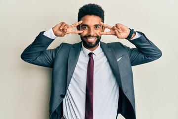 Handsome hispanic man with beard wearing business suit and tie doing peace symbol with fingers over face, smiling cheerful showing victory