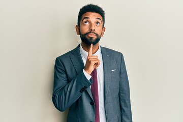 Handsome hispanic man with beard wearing business suit and tie thinking concentrated about doubt...