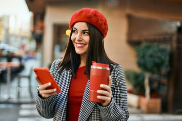 Young hispanic woman using smartphone and drinking coffee at the city.