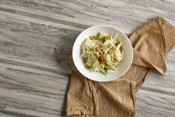 Waldorf salad with celery, apples and walnuts on a light wooden background in rustic style
