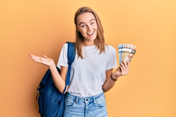 Beautiful blonde woman wearing student backpack and holding canadian dollars celebrating...